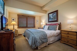 A bedroom with a bed, a nightstand, a dresser, a window with blinds, a lamp, and a painting on the wall. - TL2305 | Vaulted Ceiling | A/C | 10 Hot Tubs | 4 Pools | Close to Mtn (Steamboat Springs)