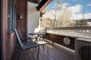 A wooden deck with a table and chairs, a wall-mounted heater, and a view of a snowy landscape. - TL2306 | Top floor | Amenities Galore | Beautiful Residence | A/C (Steamboat Springs)