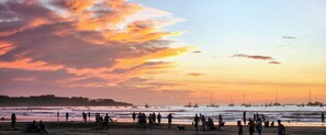 Eine Strandansicht mit Menschen und Booten im Sonnenuntergang.