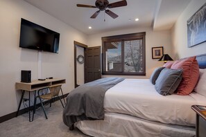 A bedroom with a bed, a desk, a chair, a television, a ceiling fan, a window with blinds, and a wall-mounted artwork. - TL2311 | Great Views | Beautiful Top Floor with Vaulted Ceiling | Winter Shuttle (Steamboat Springs)