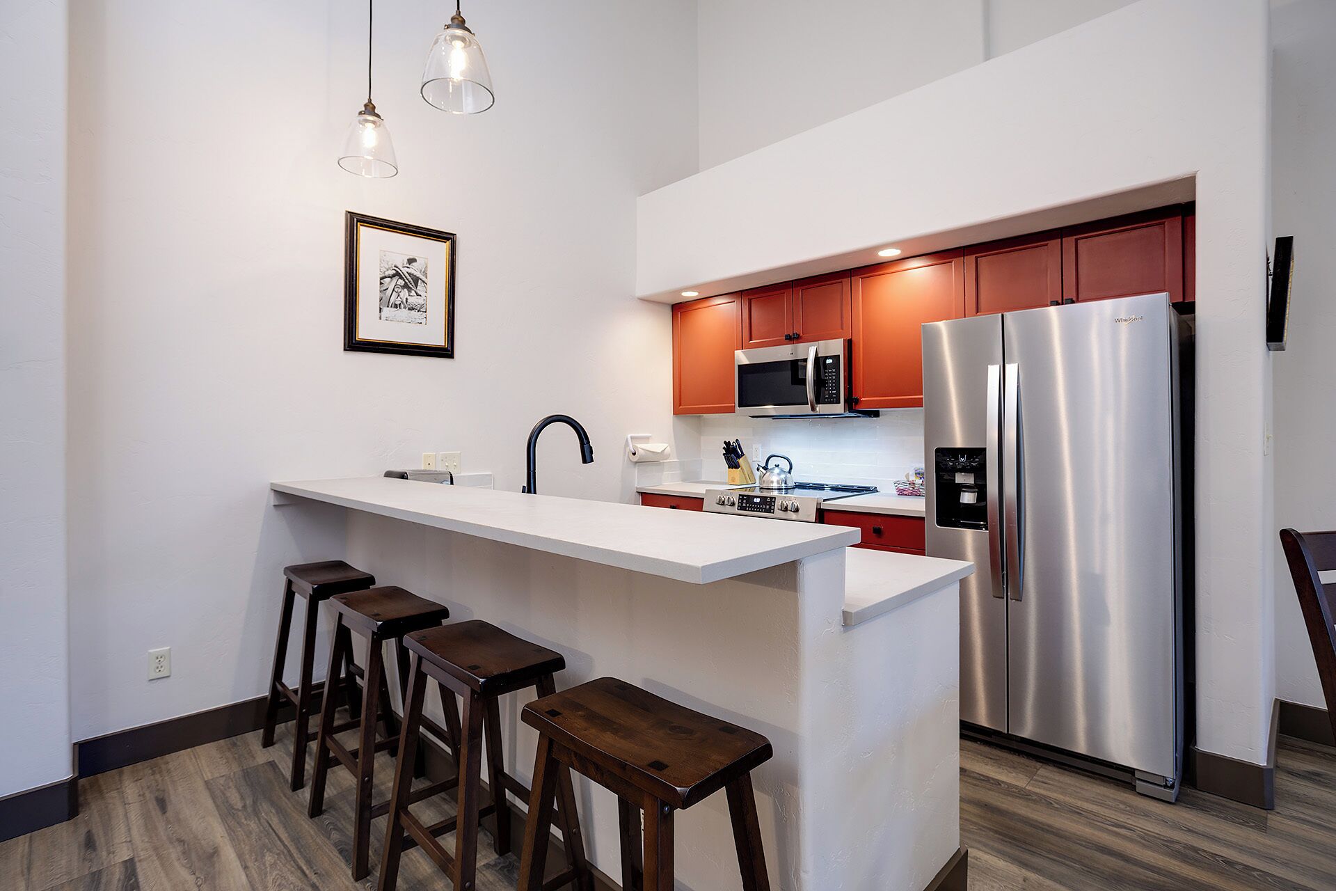 A modern kitchen with a central island, stainless steel appliances, and wooden stools.