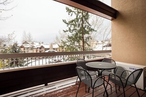 A balcony with a table and chairs, overlooking a snowy residential area with houses and trees. - TL2312 | Lovely Top Floor Condo | Beautiful Views | 10 Hot Tubs | A/C (Steamboat Springs)