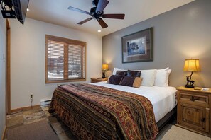 A bedroom with a bed, a ceiling fan, a window with blinds, a bedside table with a lamp, and a framed picture on the wall. - TR1110 | Perfect Getaway | A/C | 10 Hot Tubs | 4 Pools (Steamboat Springs)