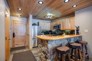 Una cucina con mobili in legno, un'isola in pietra e un soffitto rustico.