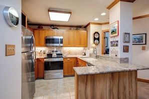 A kitchen with wooden cabinets, stainless steel appliances, and a granite countertop. - TR1201 | Beautiful Home | Close to Skiing | A/C | 10 Hot Tubs (Steamboat Springs)
