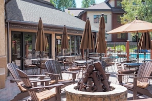 An outdoor patio area with multiple tables and chairs, umbrellas, and a decorative fire pit. - TR1201 | Beautiful Home | Close to Skiing | A/C | 10 Hot Tubs (Steamboat Springs)