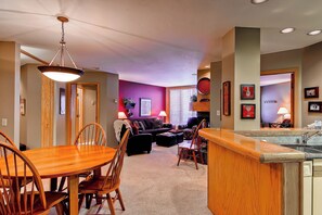 A spacious living area with a dining table and chairs, a fireplace, and a kitchen area with a bar. - TR1202 | Beautiful Décor | Close to Skiing | A/C | 10 Hot Tubs (Steamboat Springs)