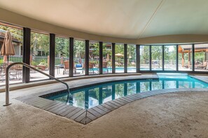 Ein Hallenbad mit freiem Blick auf die Außenpatio-Terrasse, einschließlich Sitzgelegenheiten und einem Poolbereich.