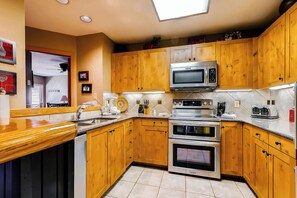 Cocina con armarios de madera, electrodomésticos de acero inoxidable y salpicadero de azulejos.