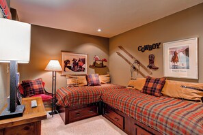 A bedroom with two beds, a framed picture of a cowboy, a mounted pair of skis, and a cowboy boot on the wall. - TR1202 | Beautiful Décor | Close to Skiing | A/C | 10 Hot Tubs (Steamboat Springs)