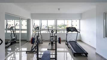 A gym with various exercise equipment, large windows, and a clean, tiled floor.