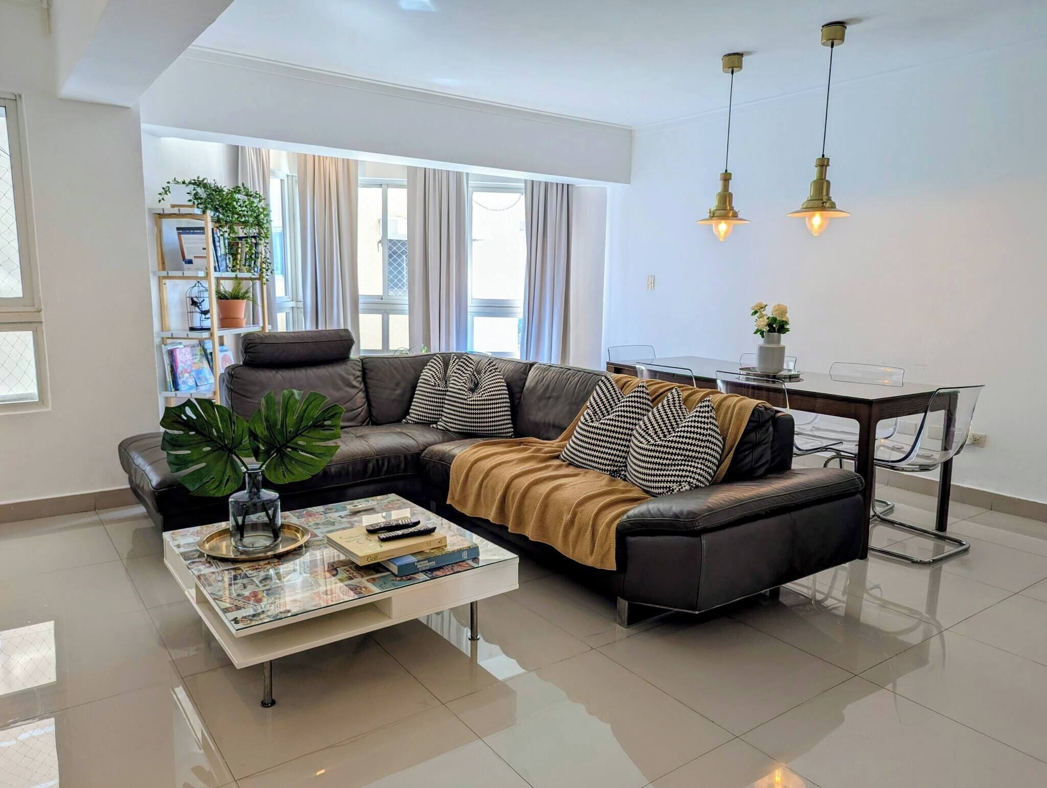 Una sala de estar moderna con un sofá modular, una mesa de centro de vidrio y un comedor con mesa y sillas de vidrio.