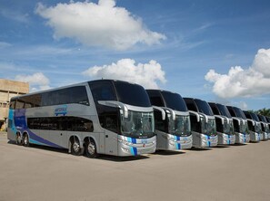 A row of buses parked in a lot with a clear sky. - 2br Kingbed Kids Play Area No Surgery (Santo Domingo)