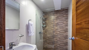 A modern bathroom with a glass-enclosed shower, a white sink, and a wooden door. - 2br Kingbed Kids Play Area No Surgery (Santo Domingo)