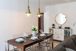 Ein Essbereich mit einem Holztisch, gedeckt für vier Personen, klaren Stühlen und zwei hängenden Pendelleuchten.