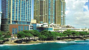 A coastal cityscape with high-rise buildings, a beach, and a clear sky. - 2br Kingbed Kids Play Area No Surgery (Santo Domingo)