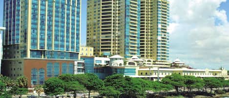A coastal cityscape with high-rise buildings, a beach, and a clear sky.
