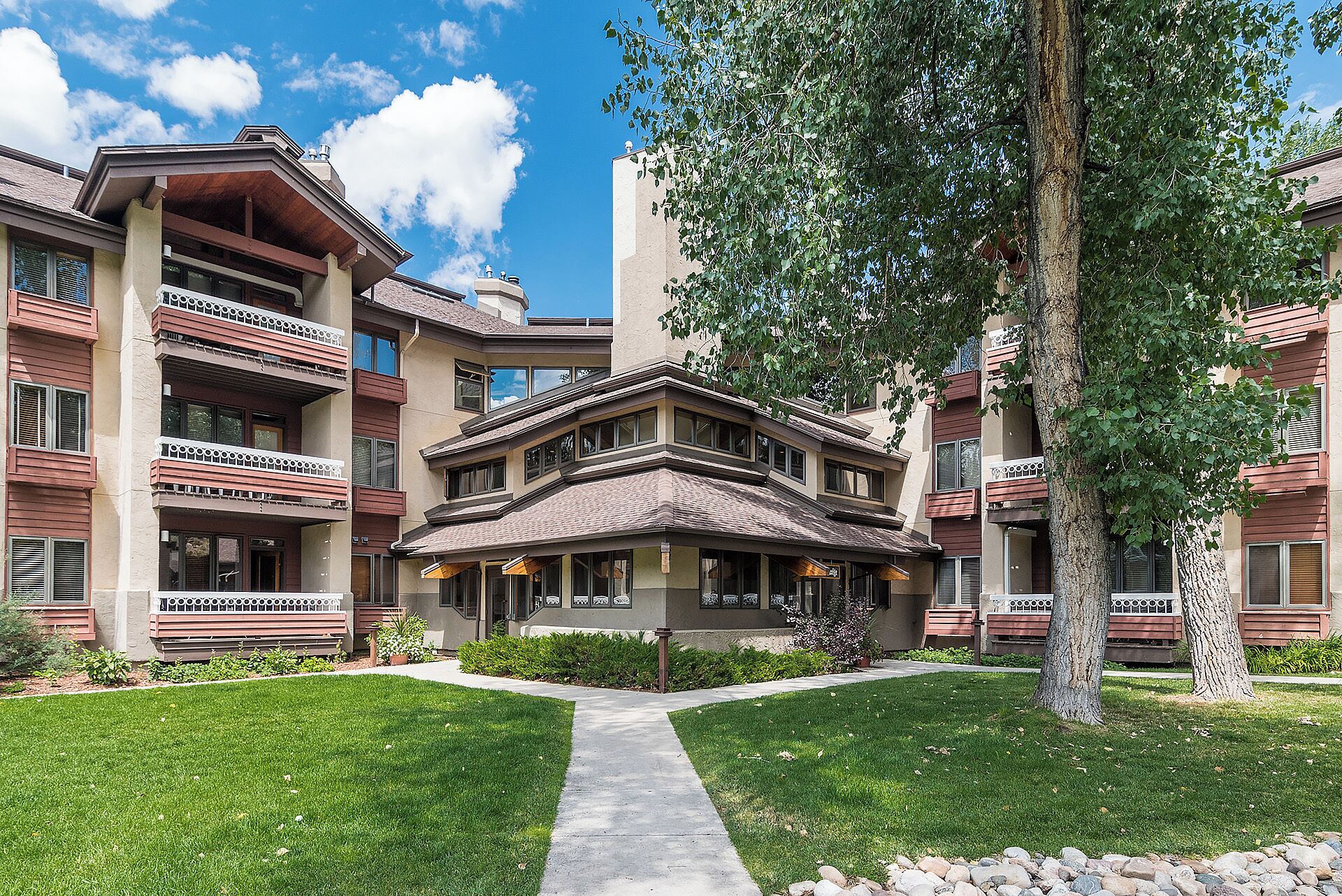 A multi-story residential building with balconies, a central courtyard, and a well-maintained lawn.