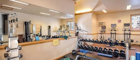 A gym with various exercise equipment, including treadmills, weight machines, and dumbbells.