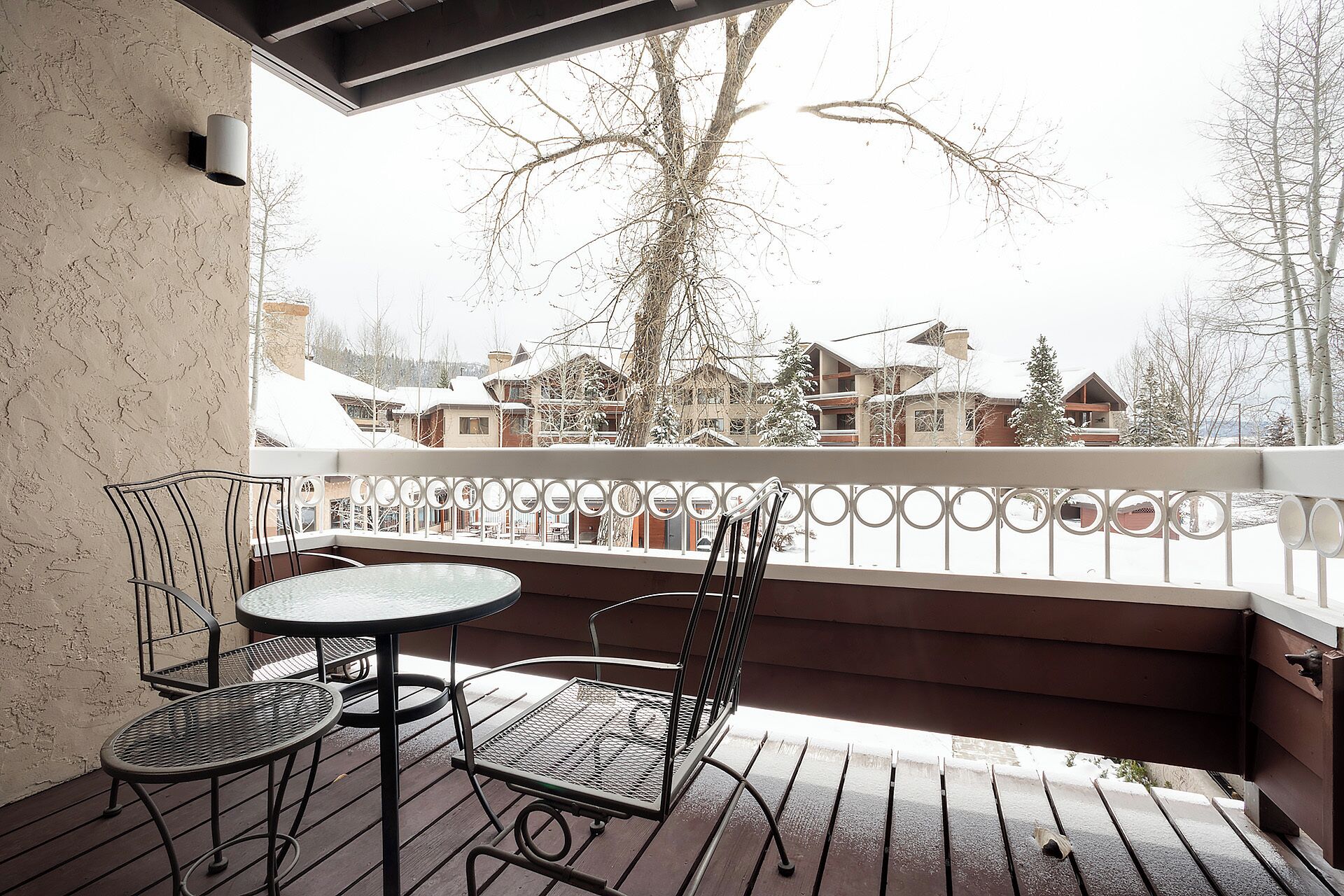 Un balcon avec une table et des chaises, donnant sur un village enneigé.