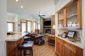 A spacious kitchen with a stone fireplace, wooden cabinets, and a bar area. - TR1211 | Phenomenal Mtn Getaway | Close to Skiing | Hot Tubs | A/C (Steamboat Springs)