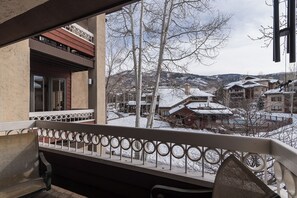 Ein Balkon mit Metallgeländer, der einen verschneiten Ort mit traditioneller Bebauung überblickt.