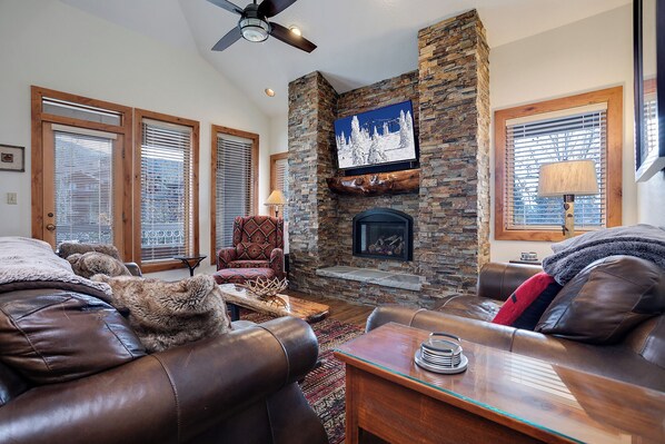 A cozy living room with leather sofas, a stone fireplace, and a television mounted above it. - TR1211 | Phenomenal Mtn Getaway | Close to Skiing | Hot Tubs | A/C (Steamboat Springs)