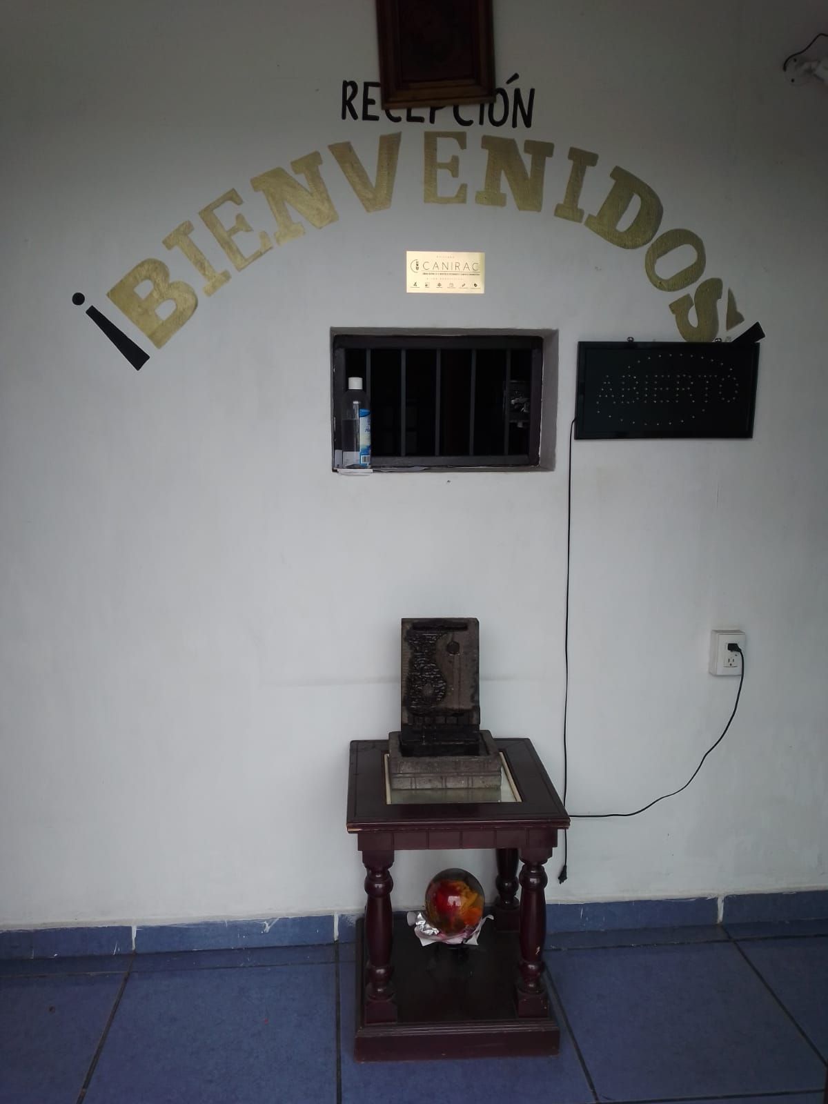 Un área de recepción con un cartel de bienvenida, un ventanal pequeño y una placa.
