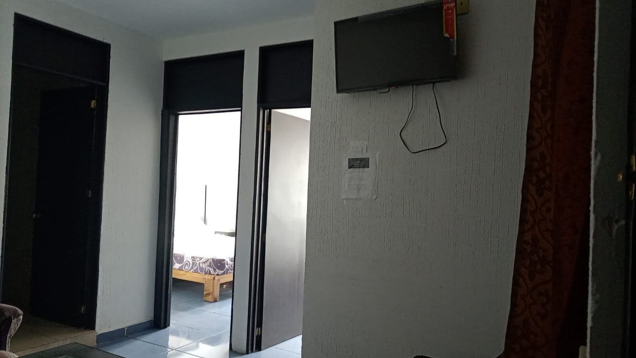 Una habitación con una puerta corredera que da a un balcón, un televisor de pantalla plana montado en la pared y una cortina estampada.