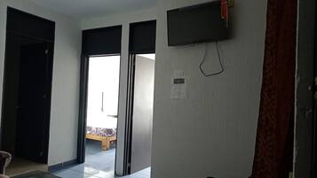 Una habitación con una puerta corredera que da a un balcón, un televisor de pantalla plana montado en la pared y una cortina estampada.
