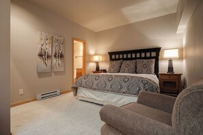 A bedroom with a bed, two bedside tables with lamps, a chair, and artwork on the wall. - TR1302 | Nicely Updated Condo | Ski Lockers | A/C | 10 Hot Tubs (Steamboat Springs)