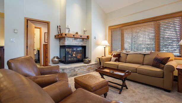 A living room with leather sofas, a fireplace, a wooden coffee table, and a window with blinds. - TR1303 | Great Layout | 10 Hot Tubs | Winter Shuttle | Close to Slopes | 4 Pools (Steamboat Springs)