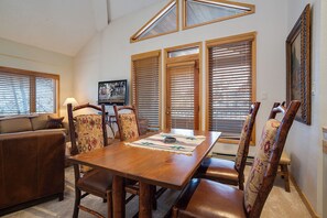 A dining area with a wooden table, leather chairs, and a television mounted on the wall. - TR1303 | Great Layout | 10 Hot Tubs | Winter Shuttle | Close to Slopes | 4 Pools (Steamboat Springs)