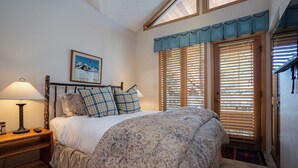 A bedroom with a bed, a nightstand, a lamp, a framed picture on the wall, and a window with blinds. - TR1303 | Great Layout | 10 Hot Tubs | Winter Shuttle | Close to Slopes | 4 Pools (Steamboat Springs)