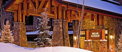 A lodge with a stone facade, wooden beams, and a sign reading "BEAR LODGE."