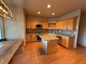 A kitchen with wooden cabinets, a granite countertop island, and a built-in microwave.