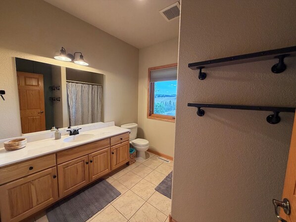 A bathroom with wooden cabinets, a white sink, a mirror, and a window with a view.
