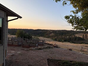 A residential property with a view of a forested landscape, a gravel driveway, and a wooden fence.