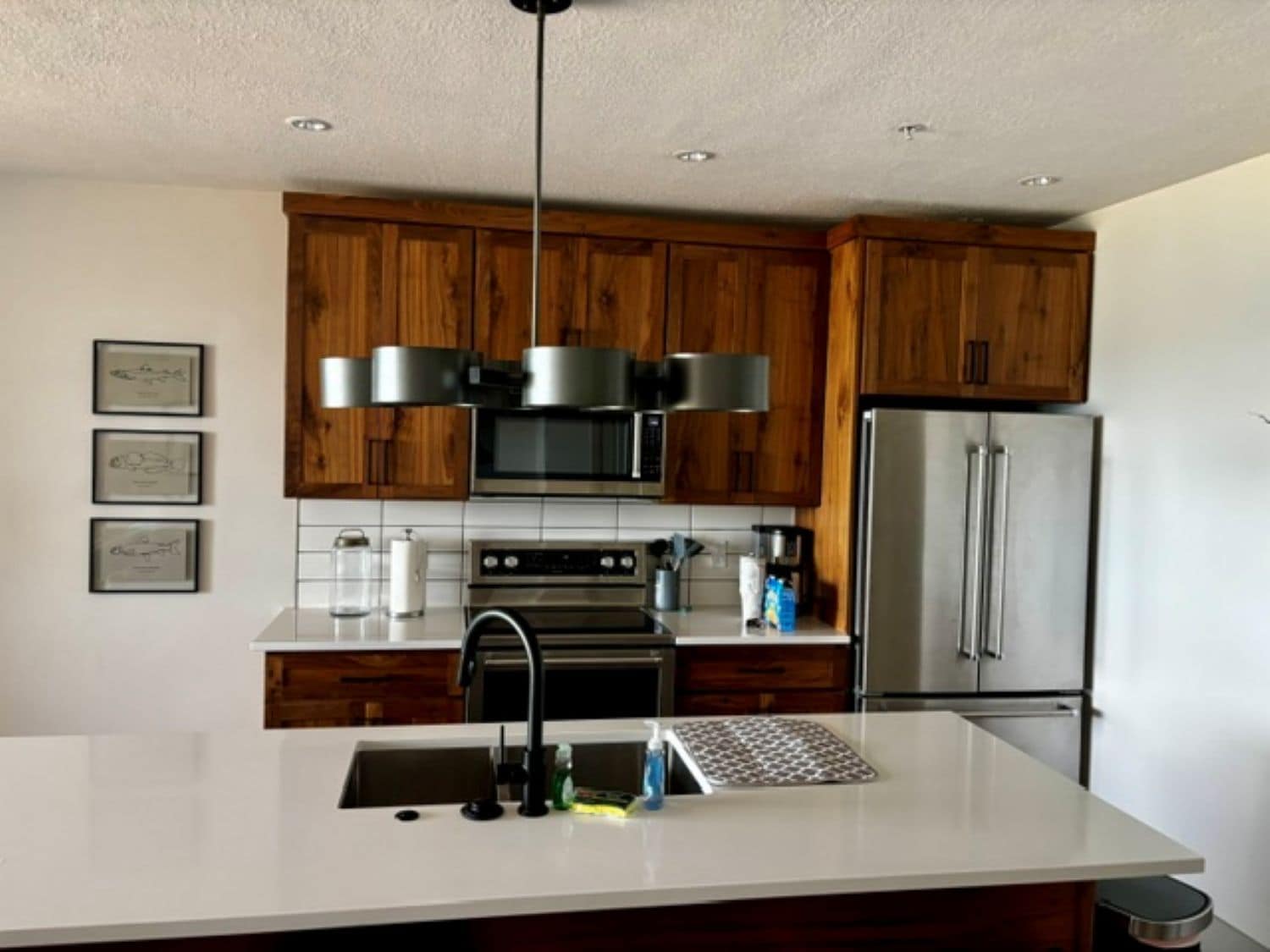 A modern kitchen with wooden cabinets, stainless steel appliances, and a white countertop.