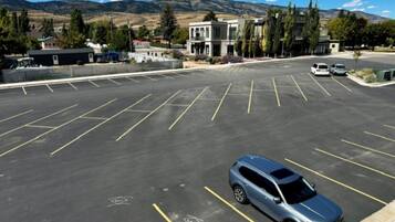 A parking lot with multiple parking spaces, a few cars, and a building with a modern design in the background.