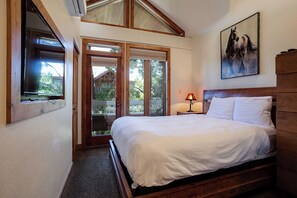 A bedroom with a wooden bed, a nightstand, a lamp, and a painting on the wall. - TR1304 | Perfect Mountain Getaway | Modern Décor | A/C | Hot Tubs (Steamboat Springs)