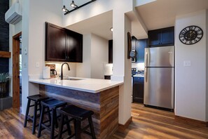 Una cocina moderna con armarios de madera oscura, un refrigerador de acero inoxidable y una encimera blanca.