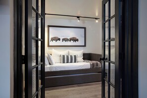 Ein Schlafzimmer mit einem Bett, Kissen, einem gerahmten Bild an der Wand und einem Fenster mit Jalousien.