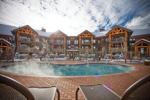 A poolside area with a hot tub, lounge chairs, and a building with multiple balconies. - CL3103 | Newly Modern| Close to Skiing | A/C | 10 Hot Tubs (Steamboat Springs)