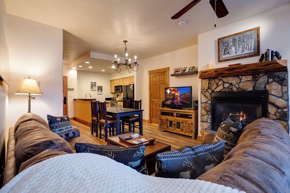 A cozy living room with a fireplace, a dining area, and a kitchen in the background. - TL2209 | Close to Slopes | A/C | 10 Hot Tubs | 4 Pools (Steamboat Springs)