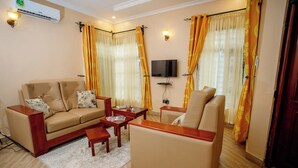 Ein Wohnzimmer mit Sofa, Sesseln, Couchtisch und einem an der Wand befestigten Flachbildfernseher.