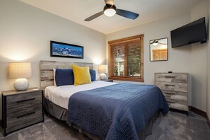 A bedroom with a bed, nightstands, a dresser, a ceiling fan, a mounted TV, and a window with blinds. - TR1102 | Mountain Getaway | 10 Hot Tubs | 4 Pools | Winter Shuttle (Steamboat Springs)