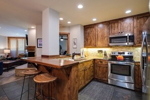 Eine moderne Küche mit Holzausstattung, Edelstahlgeräten und einer Bar mit Hockern.