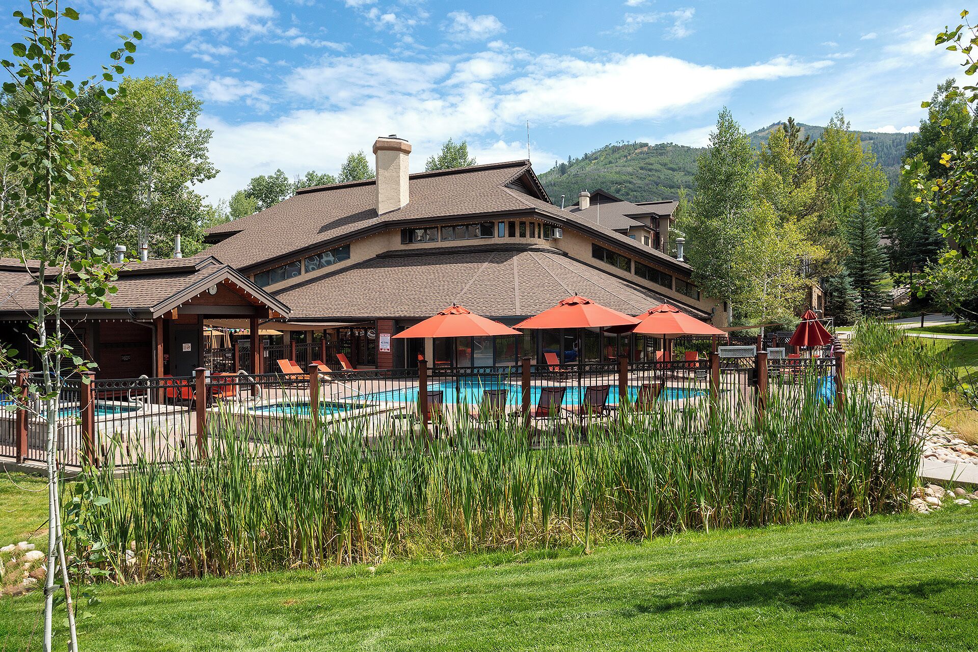 A hotel with a swimming pool, outdoor seating, and a mountainous backdrop.