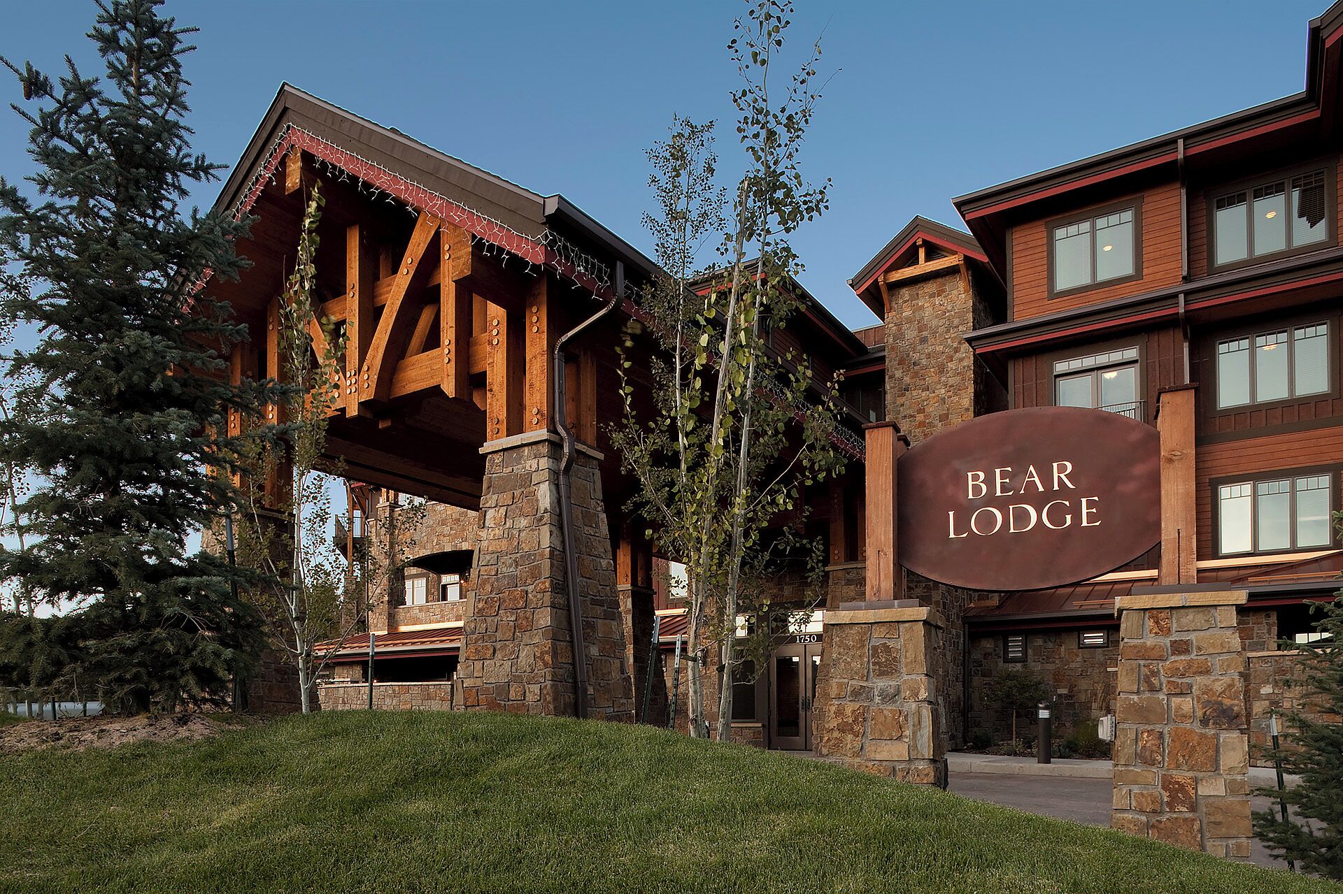 A lodge with a stone facade, wooden beams, and a sign reading "BEAR LODGE".